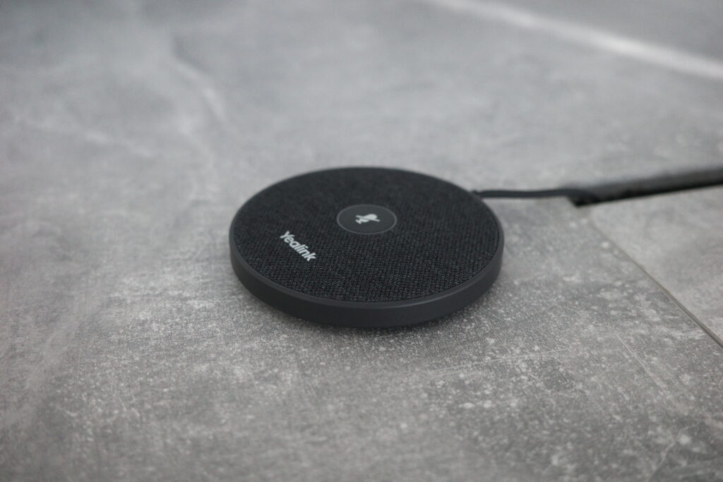 A high-quality AV microphone placed on a meeting table, designed for professional audio conferencing.